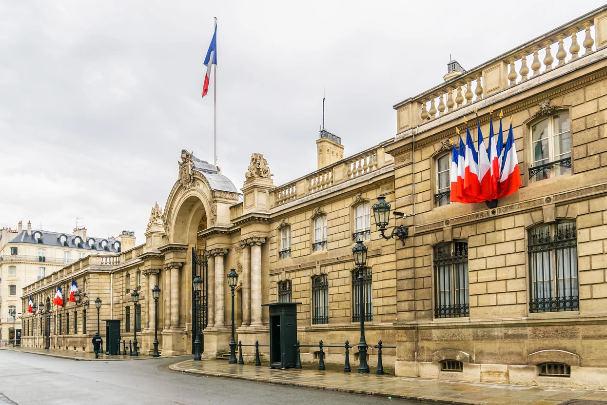 Façade officielle d'un bâtiment gouvernemental français avec drapeaux tricolores, architecture classique en pierre de taille, colonnes, balustrades sculptées