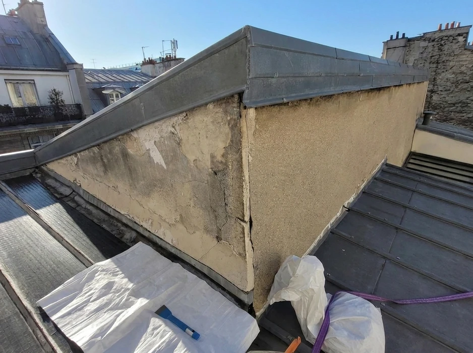 Toiture parisienne vue de dessus, structure d'acrotère en maçonnerie enduite présentant des dégradations importantes : fissures, décollements d'enduit, traces d'humidité et efflorescence
