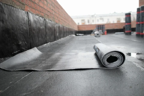Ouvriers en équipements de sécurité haute visibilité effectuent des travaux d'étanchéité sur toiture-terrasse d'immeuble