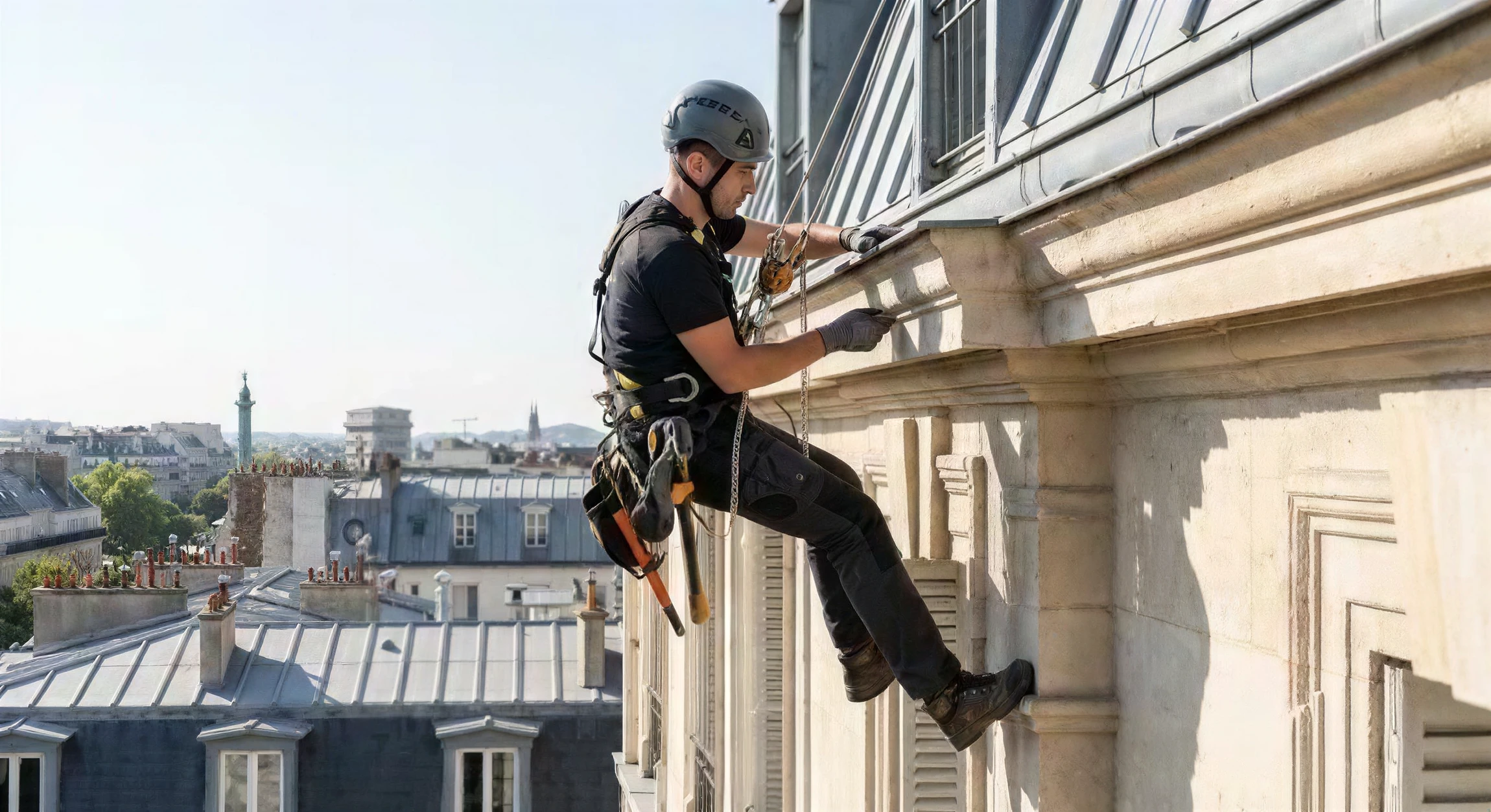 Deux ouvriers équipés de harnais de sécurité effectuent des travaux de nettoyage ou maintenance sur la façade d'un immeuble moderne multi-étages